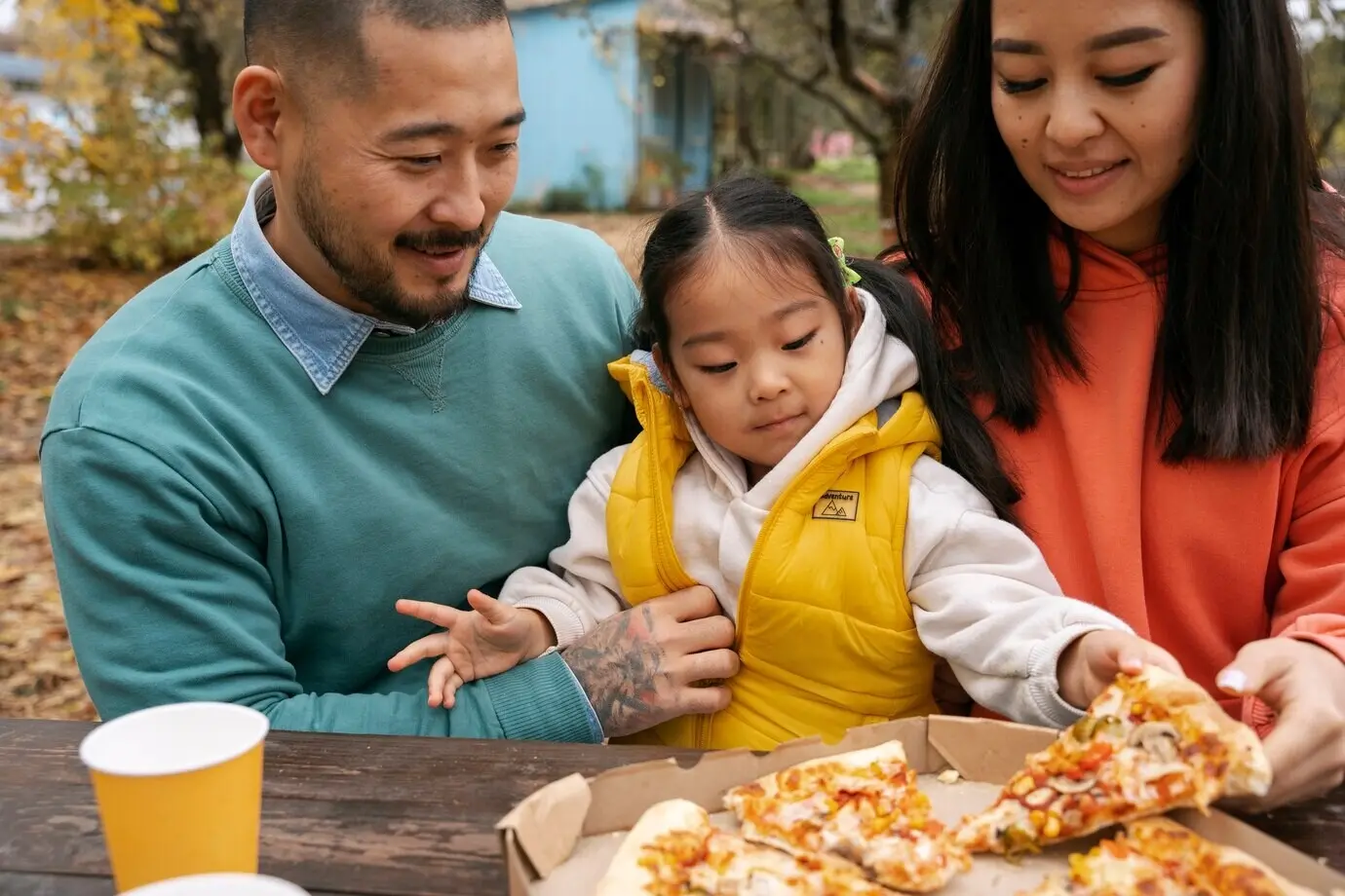 Front view of a family outside with a tasty pizza.