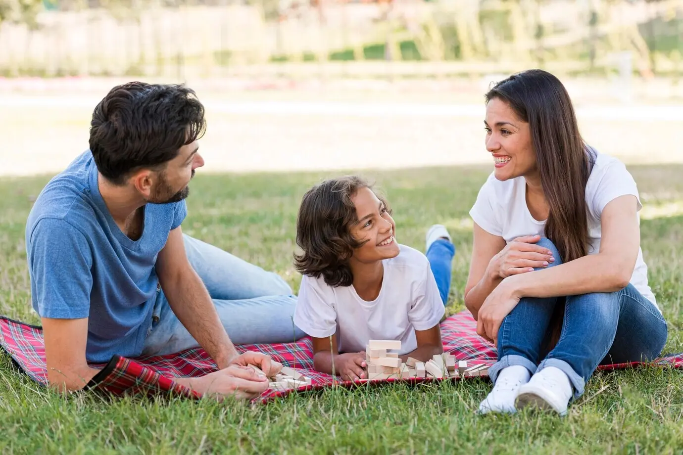 A cheerful boy in the park with his parents, enjoying their time.