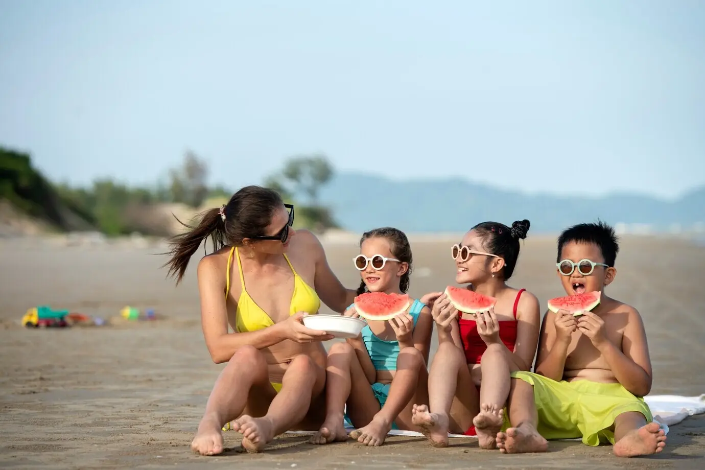 Full-length shot of a woman and children with a watermelon.